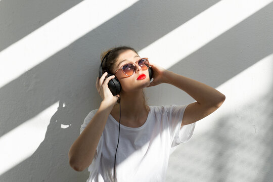 Portrait of young woman with red lips listening music with headphones