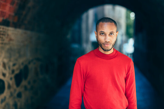Portrait of young man in an underpass wearing red pullover