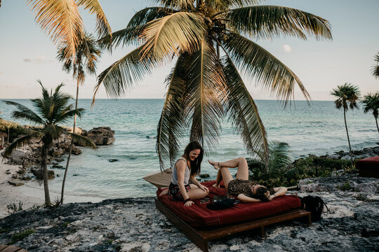 Mexico, Quintana Roo, Tulum, two happy young women relaxing on the beach