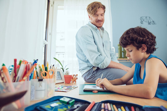 Father helping boy doing his schoolwork at home