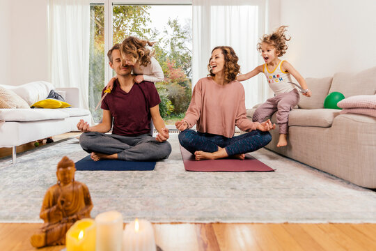 Exuberant girls with parents meditating at home