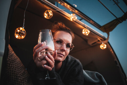 Portrait of woman with glass of white wine in van in the evening