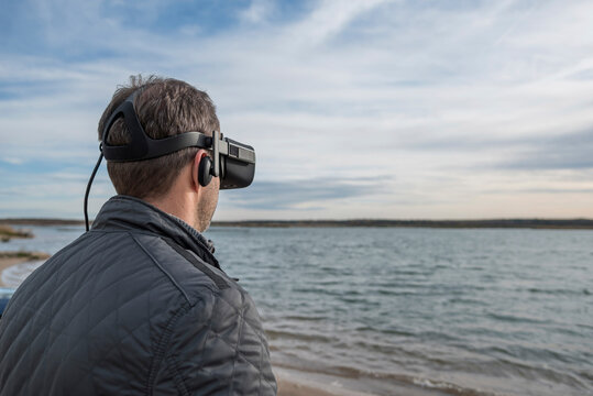 Man wearing VR glasses at lakeshore