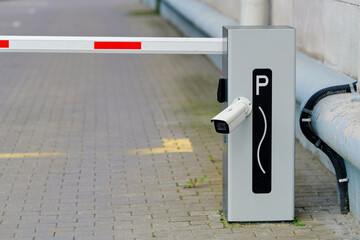 Close up of modern automatic parking barrier with security camera and white boom arm with red stripes guarding the entrance to private residential parking lot in the city during summer © Tricky Shark