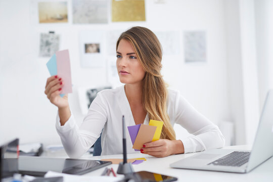 Young woman looking at notes at desk in office