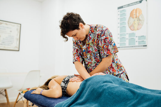 Osteopath therapist giving back massage to sportswoman in medical room