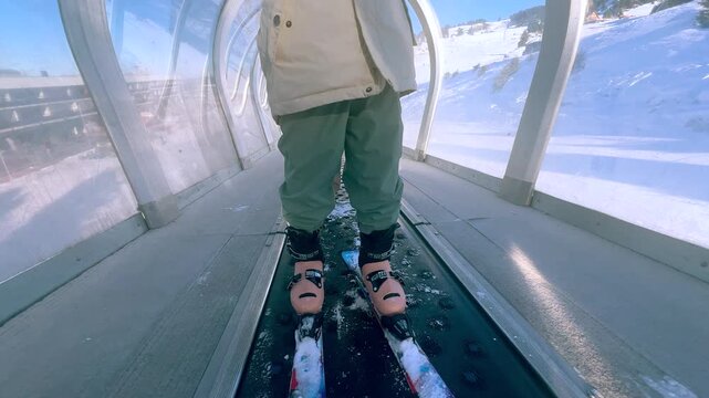 Little Girl In Helmet Riding Covered Magic Carpet Lift At Ski Resort in Chamrousse, French Alps