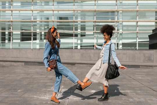 Friends greeting with giving foot bump while standing on rooftop