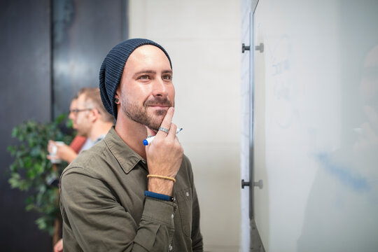 Young man thinking at whiteboard in office