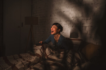 Woman watching television in bed late at night