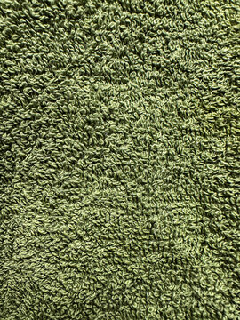 Close-up green towel texture with soft terry cloth loops and detailed textile surface. Ideal as a background for spa, bathroom, hygiene, household, fabric, and product design concepts.