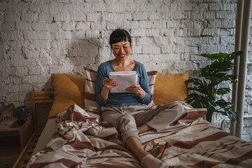 Woman smiling while writing notes in bed at home