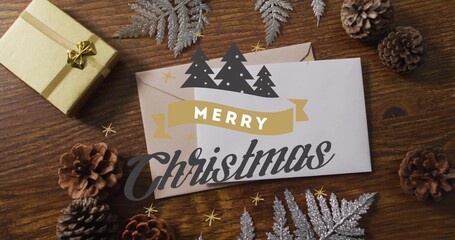 Displaying white greeting card with Merry Christmas on wood table, with gold gift and silver fern © vectorfusionart