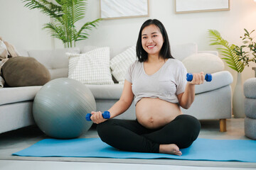 Pregnant woman exercising with dumbbells for strength training.
