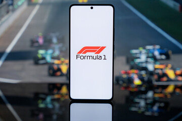 Naklejka premium the official Formula 1 logo on a white screen, set against a blurred background of F1 racing cars on a track, representing professional motorsport media and digital broadcast coverage