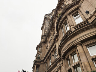 Naklejka premium Historic sandstone architecture with curved bays and ornate classical details on a Victorian building in Edinburgh, Scotland, UK photographed from street level against an overcast sky