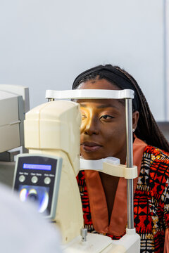 African woman getting her vision checked by ophthalmologist using non-contact tonometer (NCT)