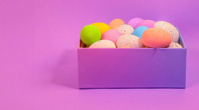 Beautiful multicoloured Easter eggs in a purple box vibrant coloured Easter egg treats on a purple flat lay celebrating the Easter holiday 