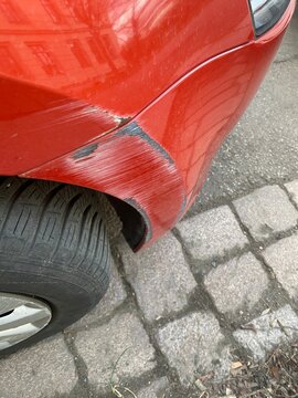 Besch&auml;digte Sto&szlig;stange an rotem Auto, Kratzer und Lackschaden nach Unfall, Thema Smart Repair, &Auml;rger, Gutachten und Versicherung, Nahaufnahme mit Copyspace