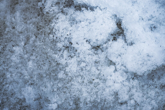 The layered structure of a snowfield and glacier lying on the bank of a mountain river in the Tien Shan Mountains of the Pamirs in Tajikistan. The texture of the snow layer lies and melts