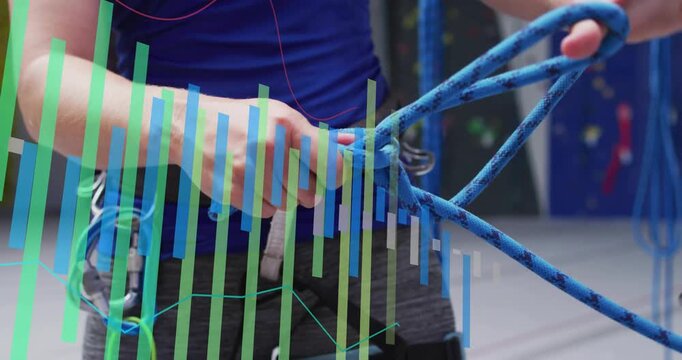Preparing to climb, climber feeding blue rope, tying harness knot, vertical bars obscuring hands