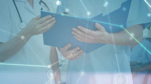 Vertical video: Overlay appearing, two MDs reviewing blue folder in clinic, stethoscope visible