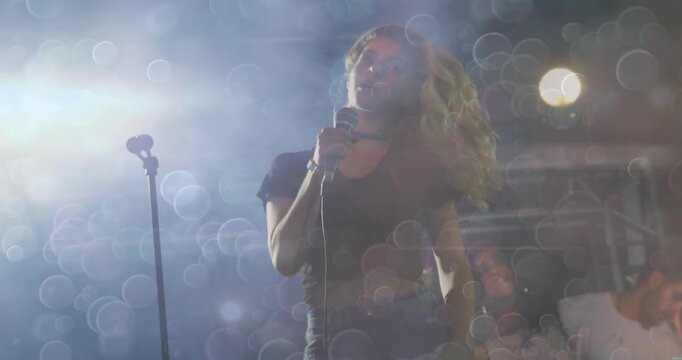 Female singer responding to opening cue, whipping head and singing with wired mic amid music haze