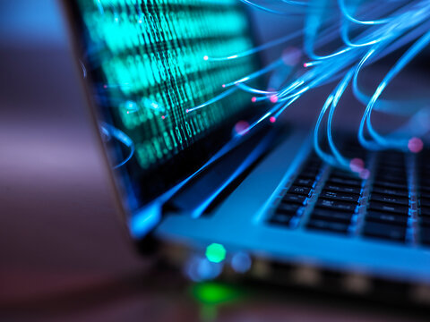 Computer virus and cyber attack on laptop with binary code and fibre optics