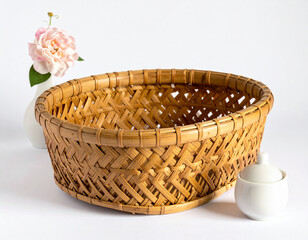 Fototapeta premium A woven bamboo basket filled with a delicate pink rose in a white vase