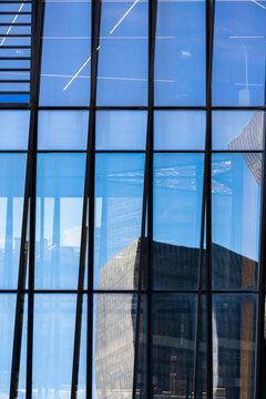 Modern corporate glass facade with window reflections and grid structure creates abstract urban architecture detail for office tower exterior background design
