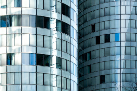 Reflective curved glass tower rises as a modern corporate skyscraper with blue windows and facade reflections for urban business architecture background