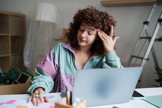 Tired young woman working remotely at home feeling stressed