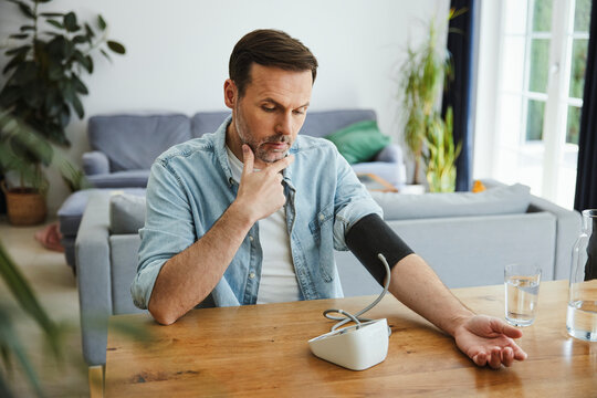 Worried person checking blood pressure with machine at home