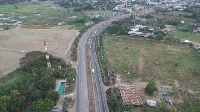 Drone aerial view of rural farmland with country road crossing agricultural fields. Countryside landscape showing agriculture