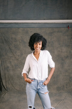 Happy young woman with Afro hairstyle standing in front of gray backdrop