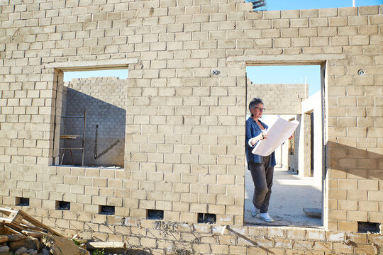 Architect holding house plans at construction site outdoors