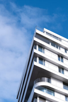 Modern architecture building facade exterior with windows in urban sky with white highrise corner design and structure against soft clouds