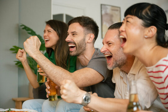 Friends celebrating and cheering while watching football match at home