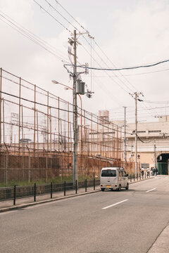 White van on empty street by metal fence on cloudy day in Osaka Japan
