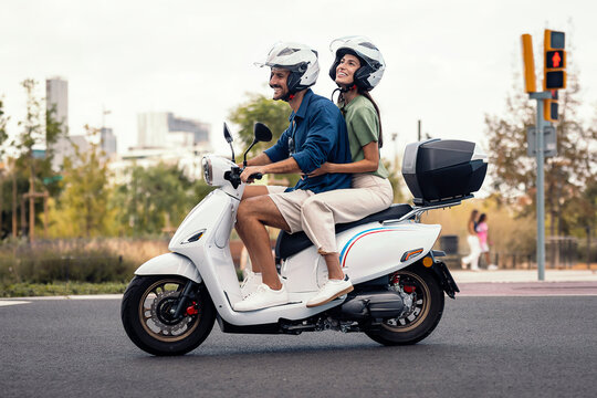 Couple enjoying an urban scooter ride on a sunny city street