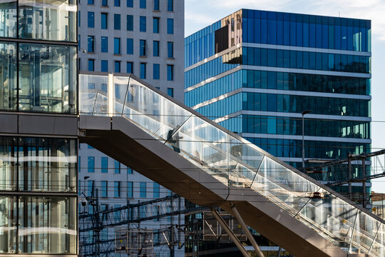 Glass skybridge staircase connecting modern office buildings with steel structure and reflections defining urban exterior architecture lines in daylight