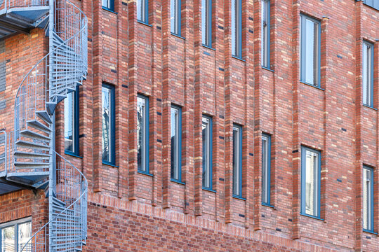 Brick industrial facade with windows and a metal fireescape staircase creating strong urban architecture texture pattern and diagonal perspective