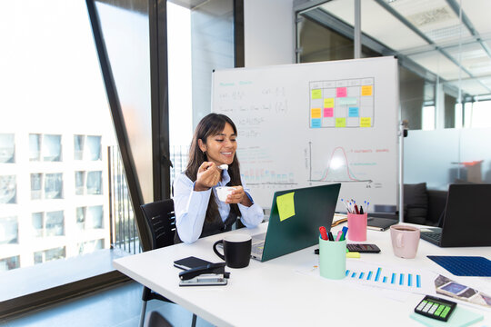 Employee eating yogurt during break at office workspace