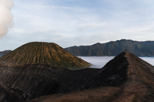 Woman hiking along volcanic ridge in Java Indonesia at sunrise