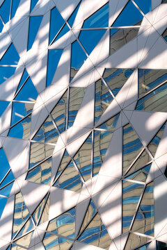 Modern facade architecture in glass triangles with bold geometry and pattern of urban reflections forming an abstract background