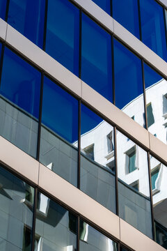 Sleek modern architecture facade of blue glass windows with diagonal pattern and urban reflections creating a clean background for design
