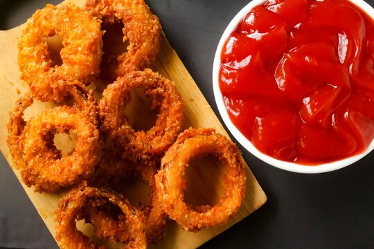 top view of onion rings on a cutting board on a black background
