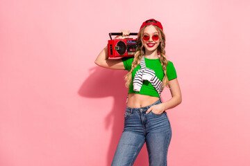 Young stylish girl with a retro boombox poses against a pink background in bright casual fashion