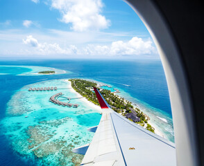 Fototapeta premium A stunning aerial view of a beautiful island in turquoise ocean seen from an airplane porthole