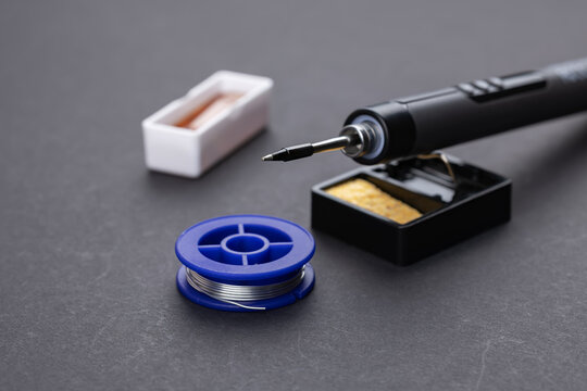 soldering iron with solder and rosin on dark background